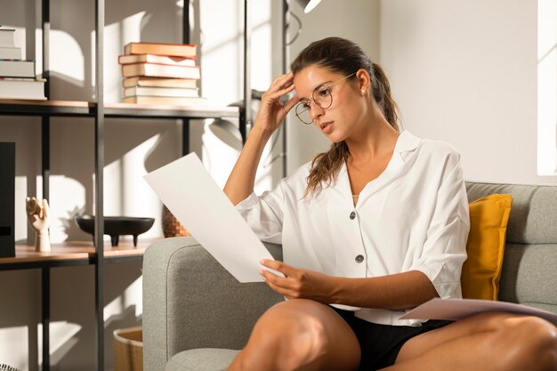 Frau auf der Couch, die Papier betrachtet