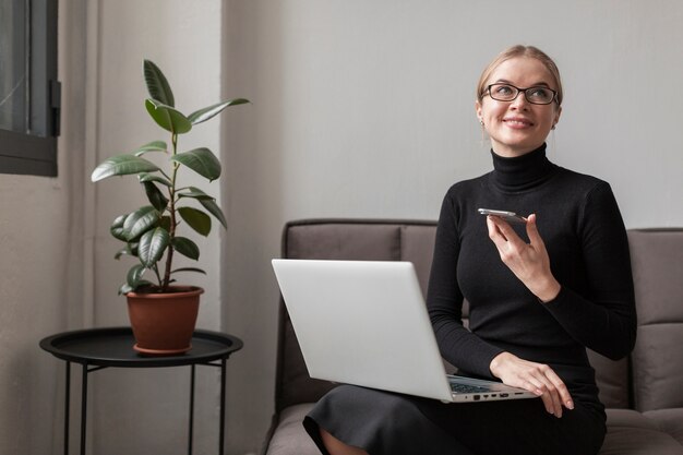 Frau auf der Couch mit Handy und Laptop