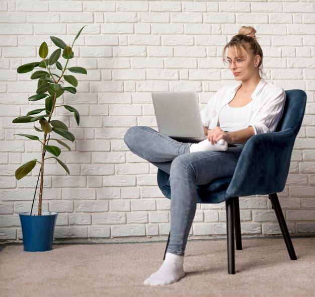 Frau auf Stuhl arbeitet am Laptop