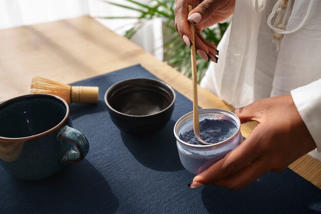 Frau aus der Vogelperspektive bereitet zu Hause blauen Matcha zu