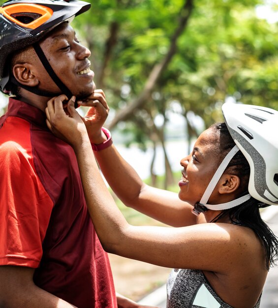 Frau befestigt einen Fahrradsturzhelm für ihren Freund
