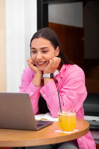 Kostenloses Foto frau bei einem videoanruf auf einem laptop in einem café