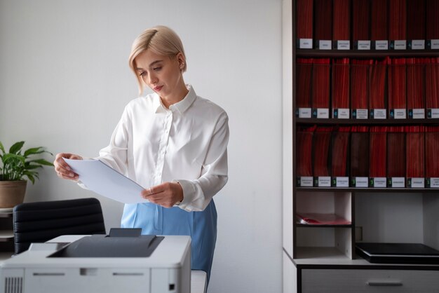 Frau benutzt den Drucker, während sie im Büro arbeitet