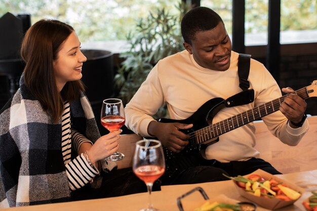 Frau beobachtet einen Mann, der auf einer Party Gitarre spielt