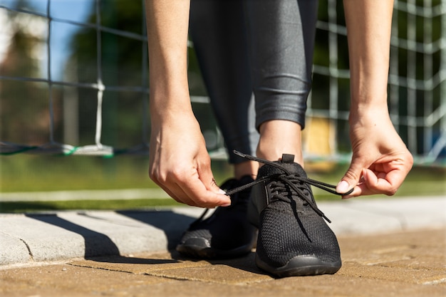 Frau bindet Sommerturnschuhe nahe den Fußballtoren