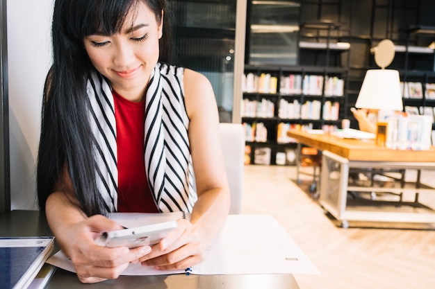 Frau chattet am Telefon in der Bibliothek