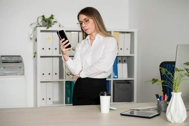 Frau checkt ihr Handy bei der Arbeit