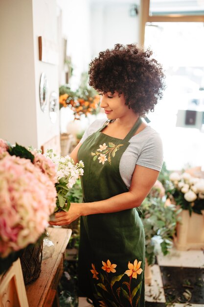 Frau des gelockten Haares, die Blumenblumenstrauß im Blumenshop vereinbart