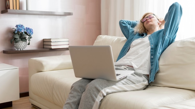 Frau, die am Laptop arbeitet und auf der Couch sitzt