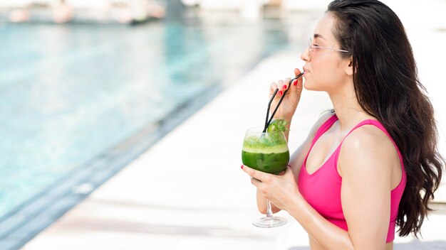 Frau, die am Pool mit einem Getränk entspannt