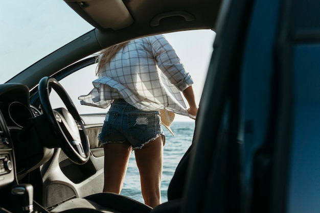 Frau, die am Strand aus dem Auto steigt