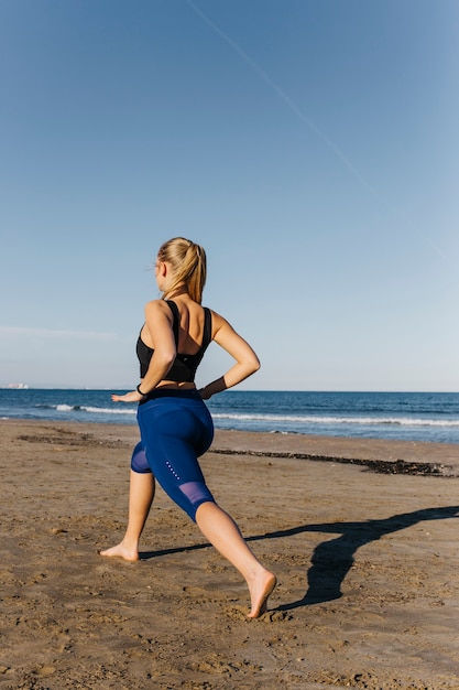 Frau, die am Strand ausdehnt