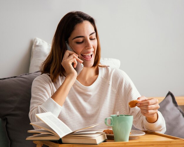 Frau, die am Telefon beim Frühstück zu Hause spricht