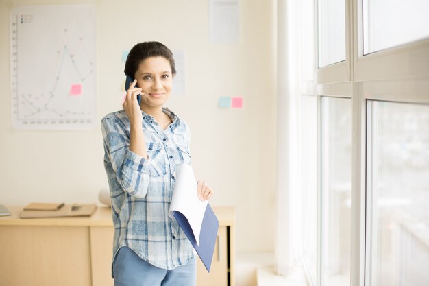 Frau, die am Telefon im Büro spricht