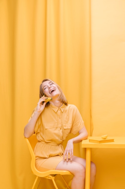 Frau, die am Telefon in einer gelben Szene spricht