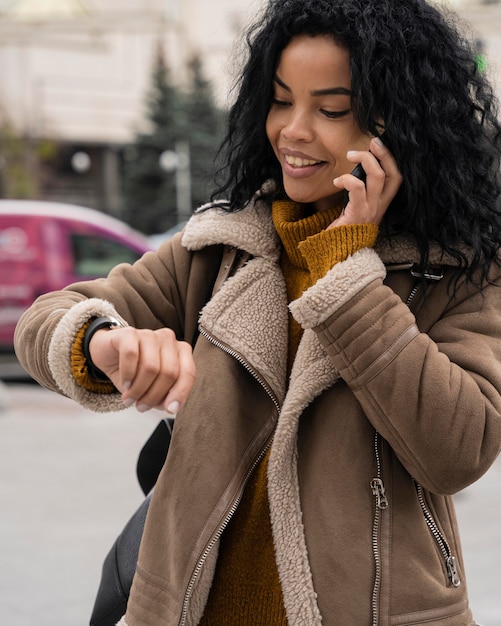 Frau, die am Telefon spricht und die Zeit überprüft