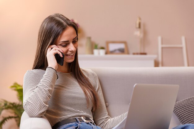Frau, die am Telefon spricht und Hausaufgaben macht