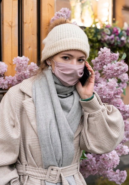 Kostenloses Foto frau, die am telefon spricht, während sie medizinische maske trägt
