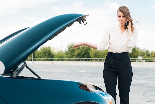 Kostenloses Foto frau, die am telefon und am auto spricht