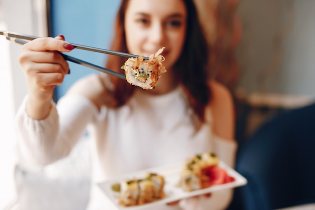 Frau, die am Tisch sitzt und Sushi im Café isst