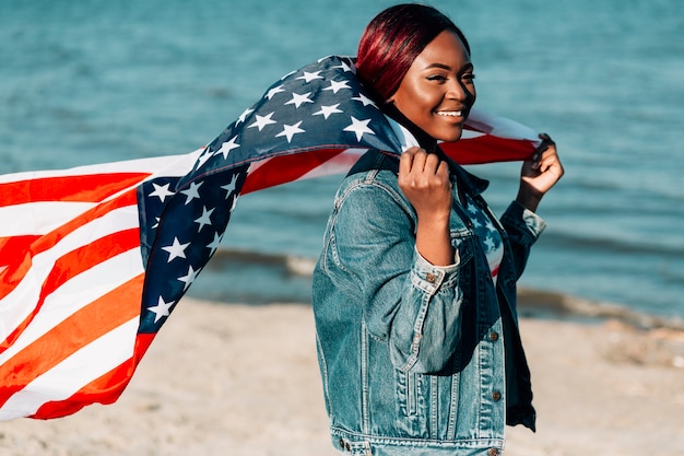 Frau, die amerikanische Flagge hinter dem hinteren Flattern im Wind hält