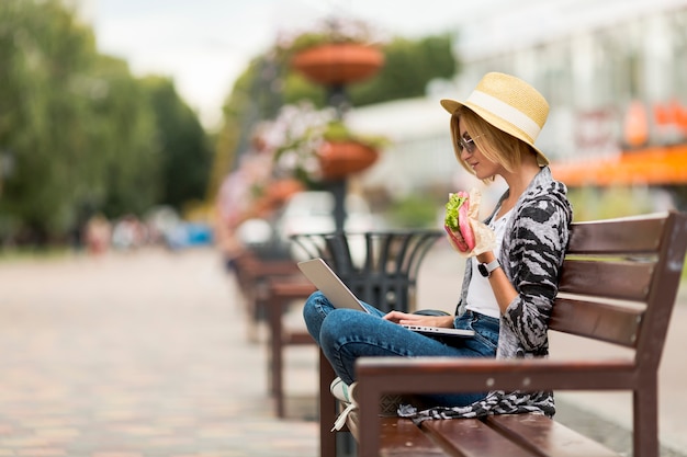 Frau, die an Bank arbeitet und isst