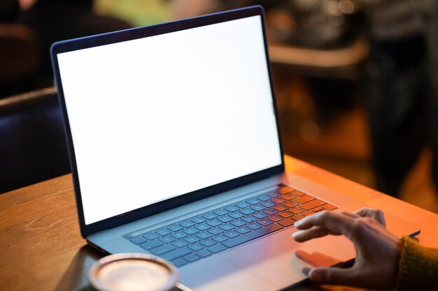 Frau, die an ihrem leeren Laptop in einem Kaffeehaus arbeitet
