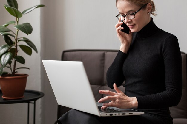 Frau, die an Laptop arbeitet und am Telefon spricht