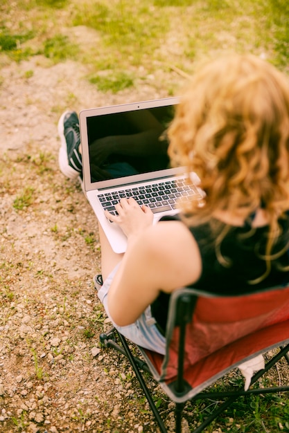 Kostenloses Foto frau, die an laptop auf naturhintergrund arbeitet