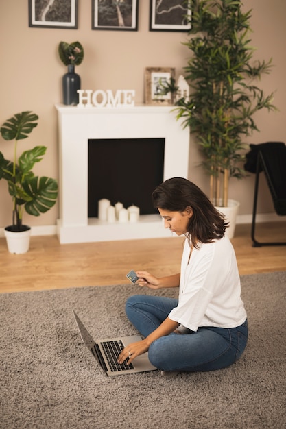 Frau, die an Laptop im Wohnzimmer arbeitet