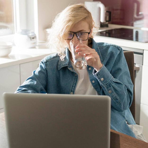 Frau, die an Laptop und Trinkwasser arbeitet