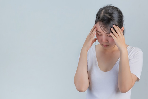 Frau, die Anzeichen von Stress auf einer grauen Wand zeigt