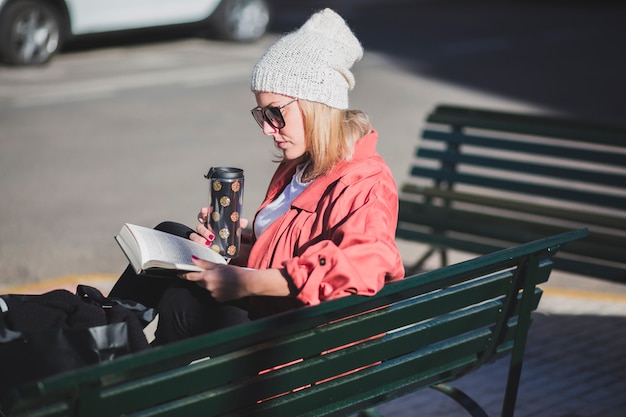 Frau, die auf Bank mit Buch stillsteht