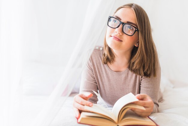 Frau, die auf Bett mit dem träumenden Buch liegt