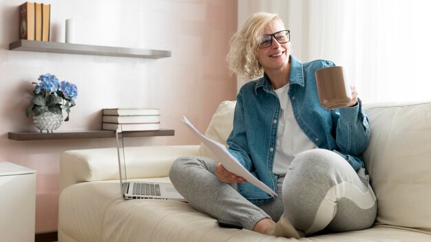 Frau, die auf Couch arbeitet und Kaffee trinkt