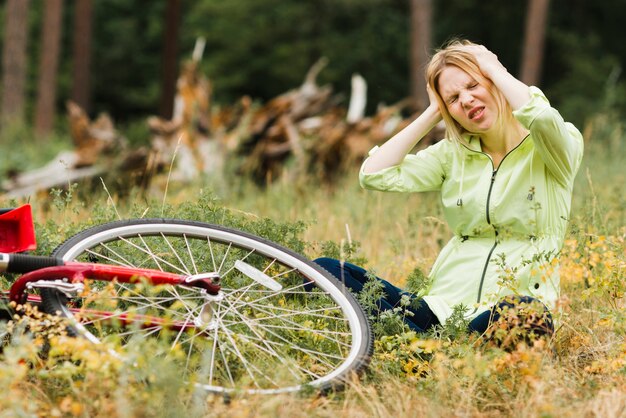 Frau, die auf dem Boden mit Kopfschmerzen sitzt