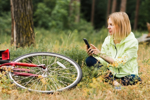 Frau, die auf dem Boden sitzt und Telefon betrachtet