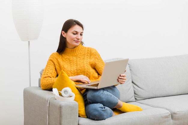 Frau, die auf dem Soda betrachtet ihren Laptop sitzt