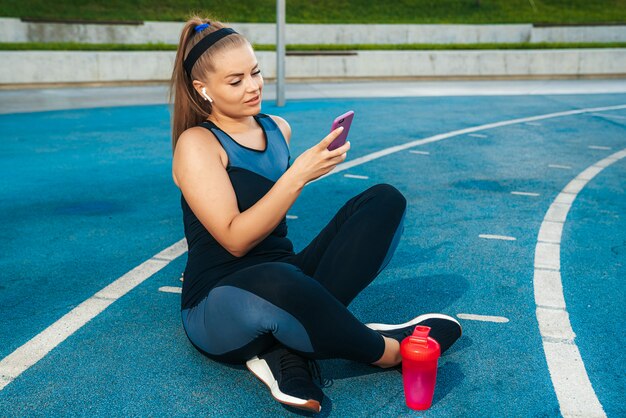 Frau, die auf dem Spielplatz mit einem Telefon in ihren Händen sitzt