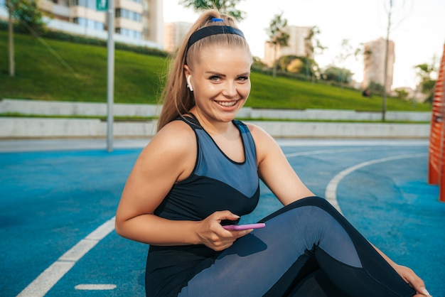 Frau, die auf dem Spielplatz mit einem Telefon in ihren Händen sitzt