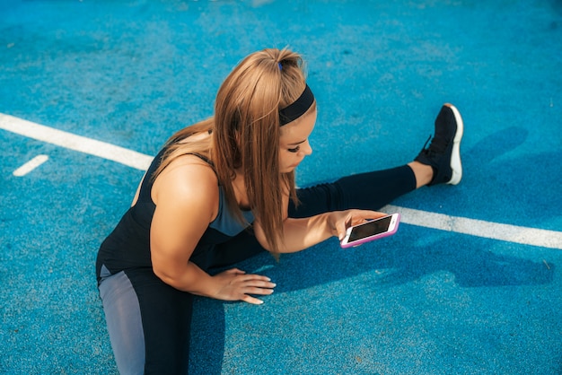 Frau, die auf dem Spielplatz mit einem Telefon in ihren Händen sitzt