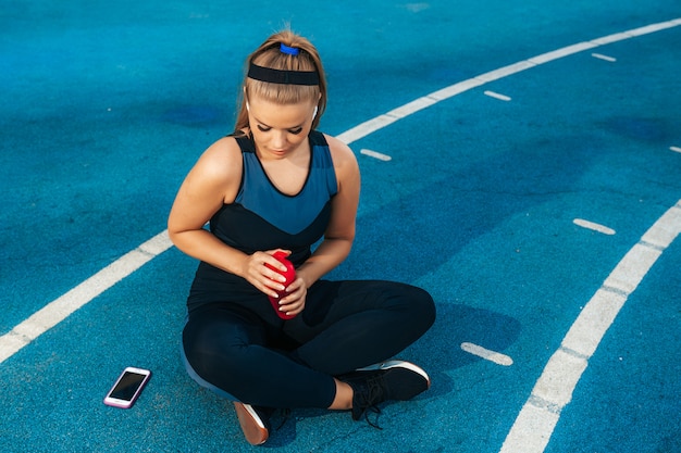 Frau, die auf dem Spielplatz mit einer Flasche Wasser sitzt