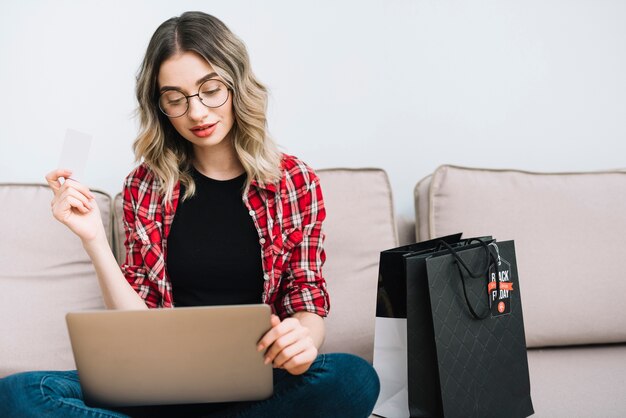 Frau, die auf der Couch studiert Verkäufe an schwarzem Freitag sitzt