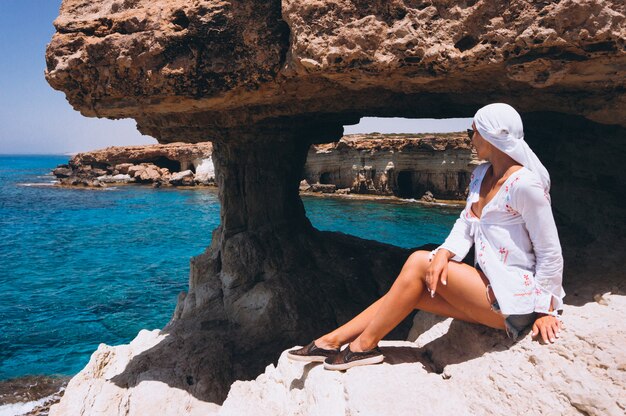 Frau, die auf die Felsenspitze durch den Ozean sitzt
