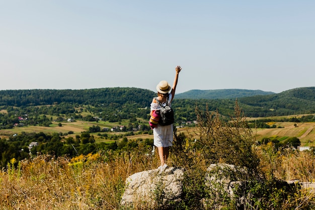 Kostenloses Foto frau, die auf einem felsen steht und eine hand in der luft anhebt