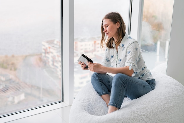 Frau, die auf einem Sitzsack mit ihrem Telefon sitzt