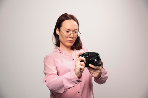 Frau, die auf einer Kamera auf einem Weiß schaut. Foto in hoher Qualität