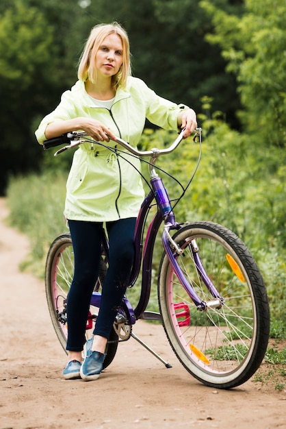 Frau, die auf Fahrrad auf Waldweg stillsteht