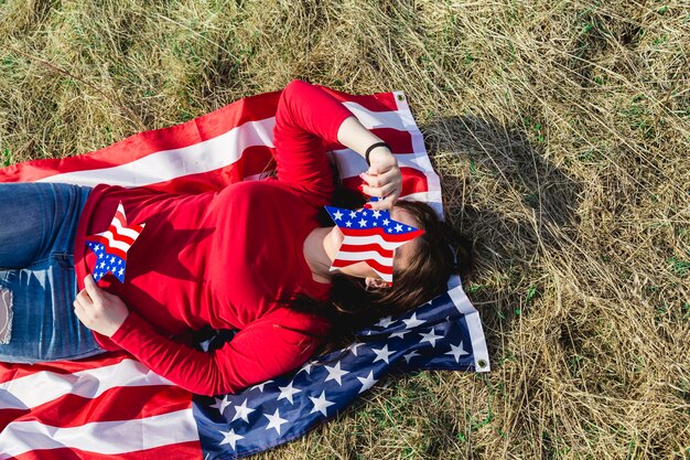 Frau, die auf Gewebe der amerikanischen Flagge auf Feld liegt