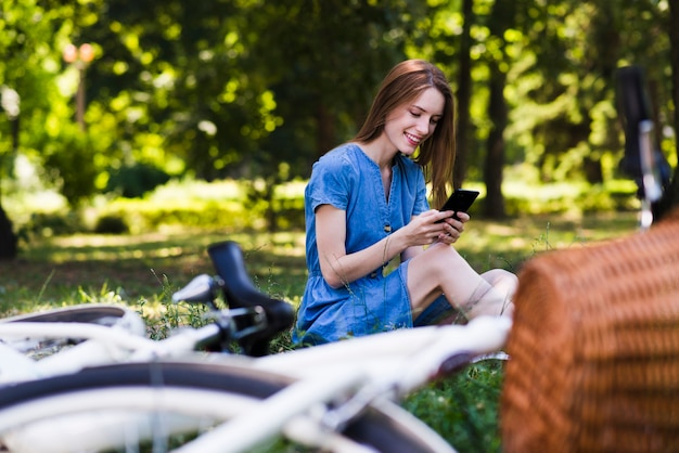 Kostenloses Foto frau, die auf gras mit defocused fahrrad sitzt